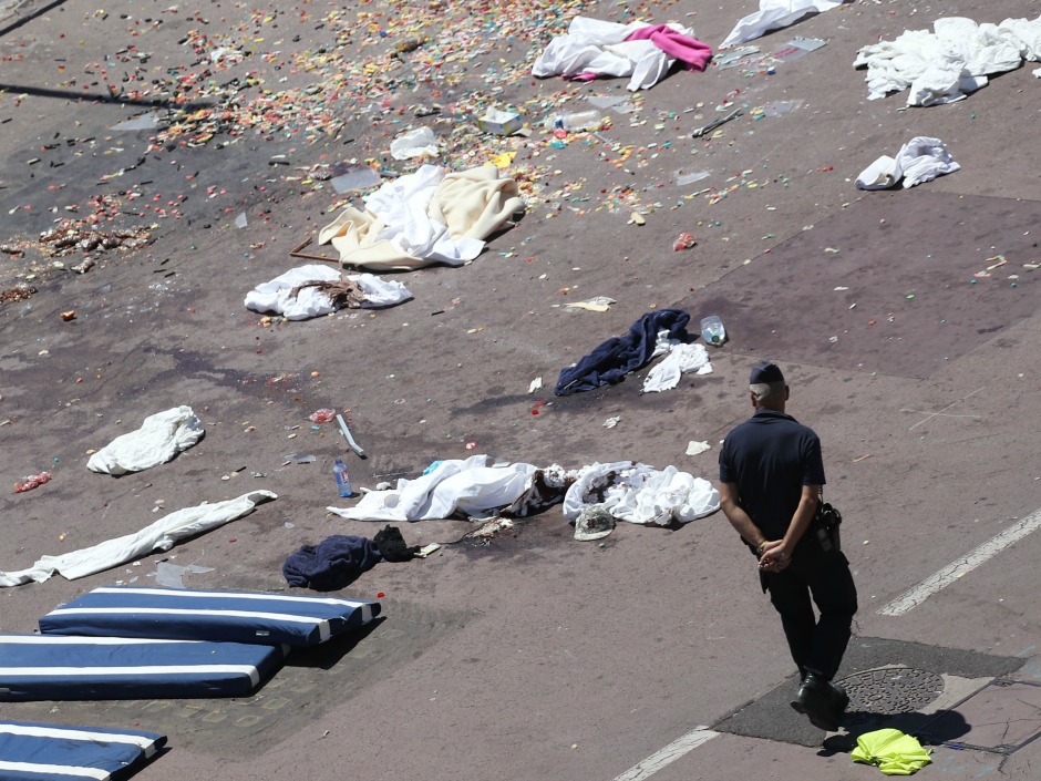 French gendarmes walk past clothes and mattresses at the site of the deadly Nice attack on July 15