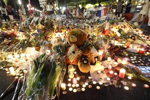 A teddy bear is laid with flowers and candles to honor the victims of an attack on the Promenade des Anglais near the area where a truck mowed through revelers in Nice southern France Saturday