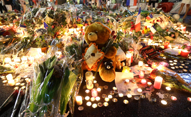 A teddy bear is laid with flowers and candles to honor the victims of an attack on the Promenade des Anglais near the area where a truck mowed through revelers in Nice southern France Saturday