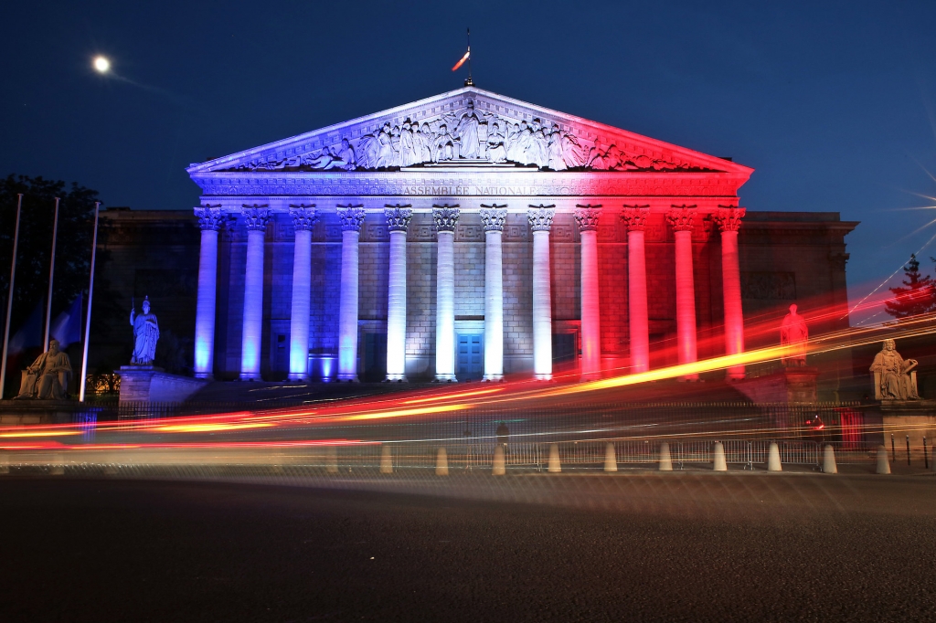 Cars pass by the National Assembly illuminated in the French national colors in honor of the victims of Thursday's attack in Nice south of France in Paris Friday