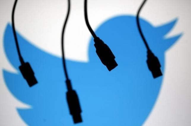 Electronic cables are silhouetted next to the logo of Twitter in this illustration