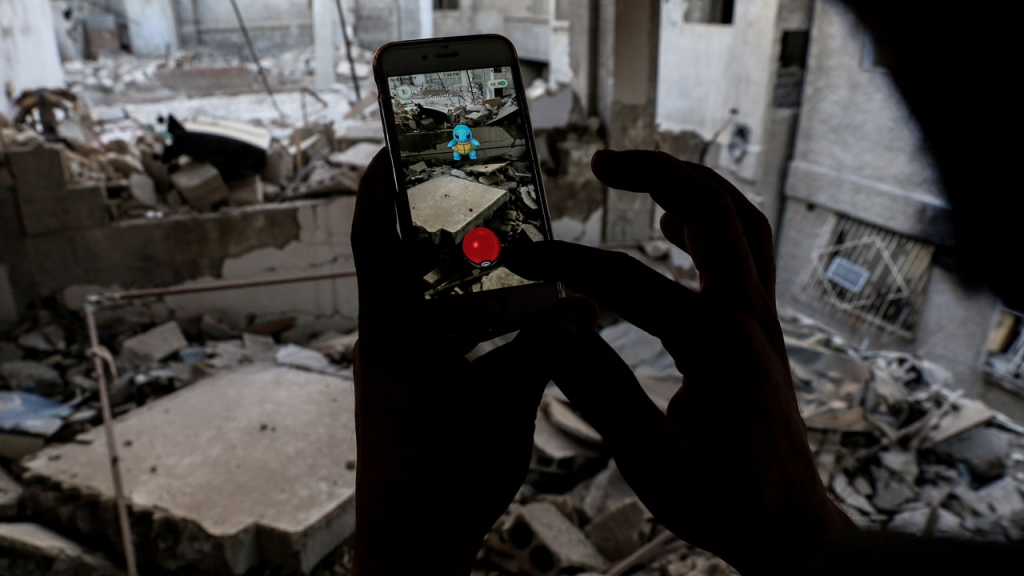 A Syrian gamer uses the Pokemon Go application on his mobile to catch a Pokemon amidst the rubble in the besieged rebel-controlled town of Douma a flashpoint east of the capital Damascus