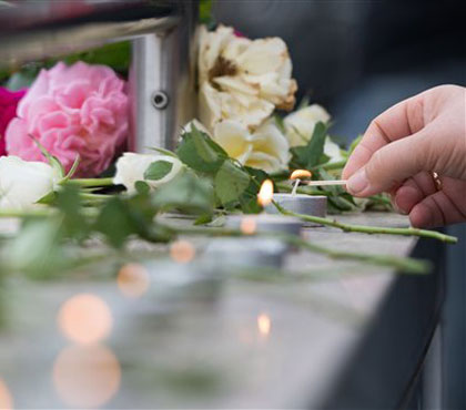 Candles are lit near a mall where a shooting took place leaving nine people dead the day before on Saturday