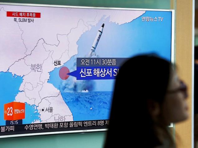 A passenger walks past a TV screen at a railway station in Seoul South Korea broadcasting a news report on North Korea's submarine-launched ballistic missile fired from North Korea's east coast port of Sinpo on Saturday