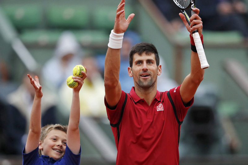 Novak Djokovic celebrates with a court boy after reaching the last four of the French Open in Paris on Thursday