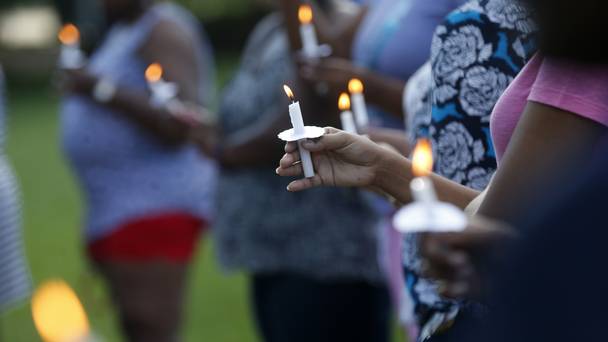 People attend a candlelight vigil for Baton Rouge police officer Montrell Jackson outside the school he attended