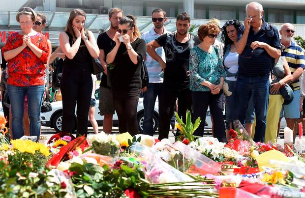 People mourn at a memorial of candles and flowers in front of the Olympia Einkaufszentrum shopping centre in Munich