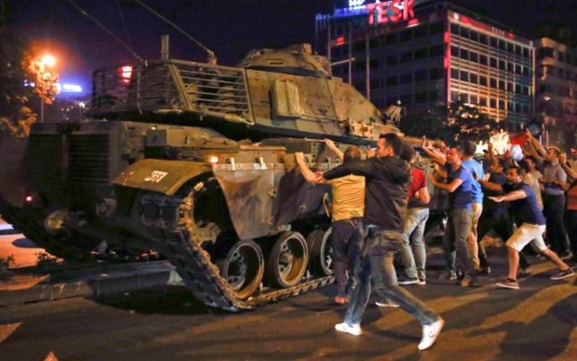 People react near a military vehicle during an attempted coup in Ankara Turkey