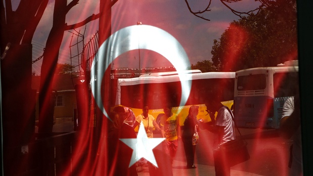 People reflected on glass with Turkish a flag at a bus station in Istanbul