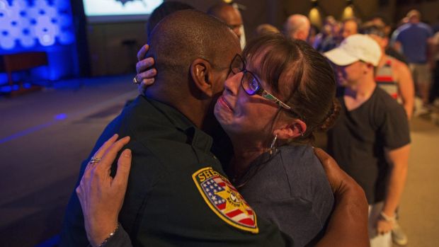 East Baton Rouge Sheriff officer Eddie Guidry is comforted by Terri Carney. Both are members of the Rock Church which