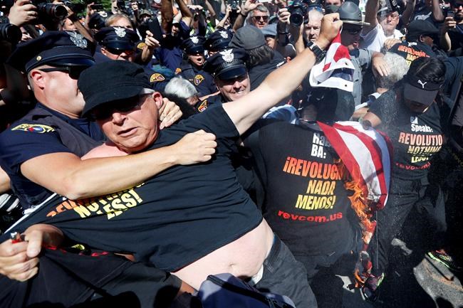 A law enforcement officer clashs with protester who is holding a burning American flag Wednesday