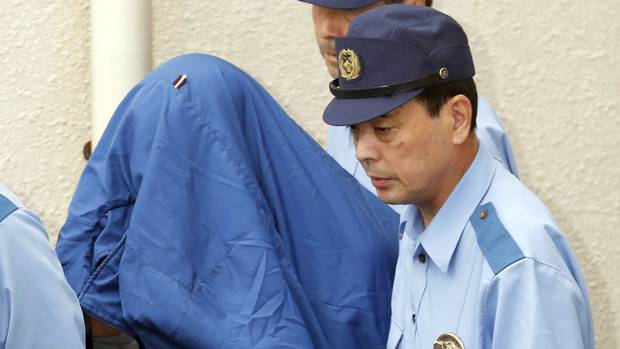 Police cover massacre suspect Satoshi Uematsu's head with a jacket as he is moved to face prosecutors