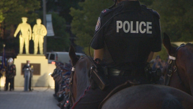 Police officers gathered in front of the memorial for fallen Ontario police officers at Queen's Park Wednesday night