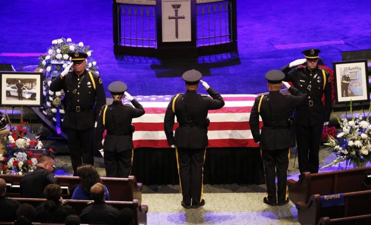 Police officers salute while next to the casket of Sr. Cpl. Lorne Ahrens before the funeral services in Plano Texas on Wednesday