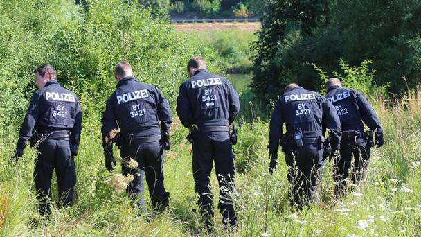 Police officers stand beside a train in Wuerzburg after a 17-year-old Afghan armed with an axe and a knife attacked passengers