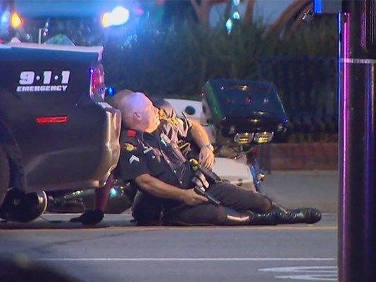 Police officers take cover as they search for suspects in the deadly shooting in downtown Dallas