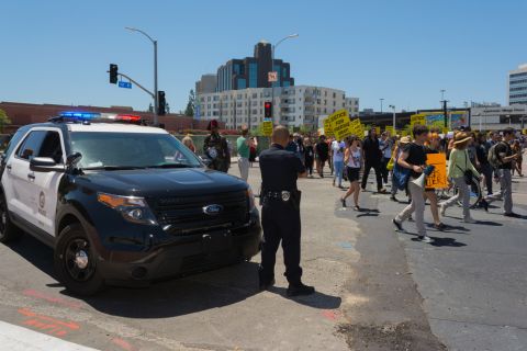 Police watch protestors in Los Angeles march against the death of Freddie Gray