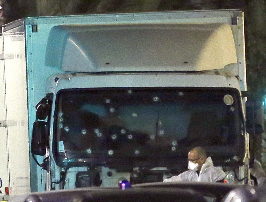 A forensic officer stands near a van with its windscreen riddled with bullets that plowed through a crowd of revelers who'd gathered to watch the fireworks in the French resort city of Nice southern France Friday