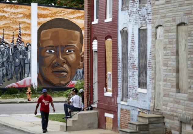 People walk by a mural depicting Freddie Gray in Baltimore on June 23 at the intersection where Gray was arrested in 2015. Prosecutors in Baltimore have dropped all remaining charges against police officers related to Gray's death while in police