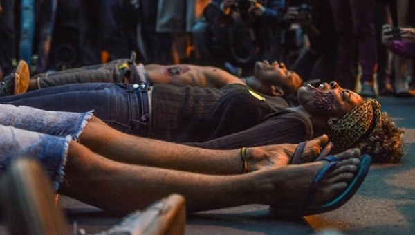 Protesters lie on the street with mock make up staging a symbolic performance representing five murdered youth