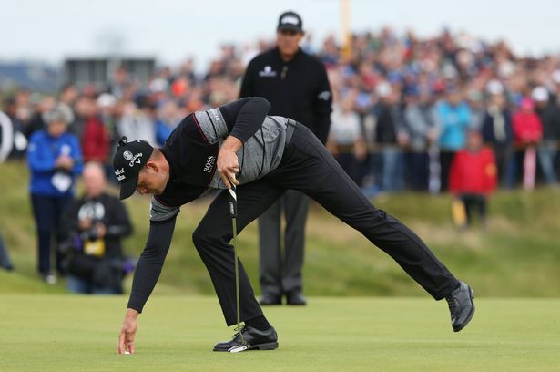 Henrik Stenson retrieves his ball after his par putt on the 13th hole