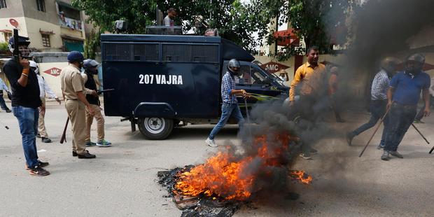 Policemen walk past flames during a protest by Dalits in Ahmadabad India. Four men belonging to the low-caste community were beaten while trying to skin a dead cow in western India