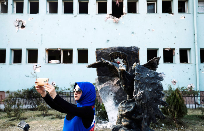 A woman takes a selfie in front of the special police forces base building in Ankara on Tuesday after it was bombed during the failed July 15 coup attempt. — AFP