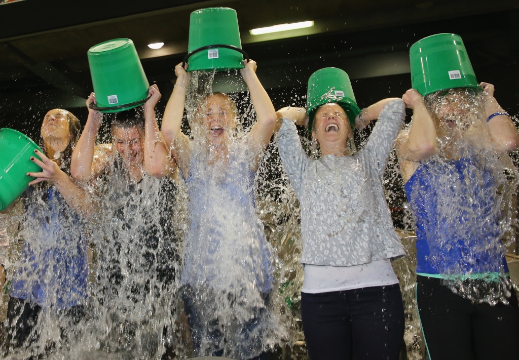 Participants tip buckets of ice water over their heads as they take part in the World Record Ice Bucket Challenge at Etihad Stadium