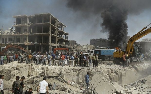 Residents gather at the site of a bomb attack in Syria’s northeastern city of Qamishli