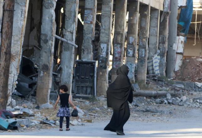 Residents walk past damaged buildings in the rebel held area of Aleppo's Bab al Hadeed district Syria