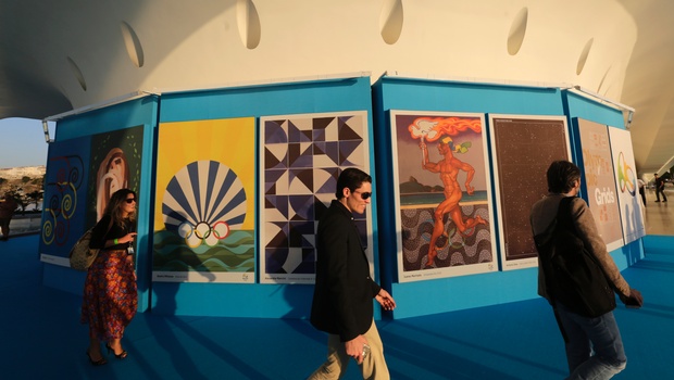 Onlookers walk by a collection of Olympic posters made by 12 Brazilian artists and a Colombian on display at the Museum of Tomorrow in Rio de Janeiro Brazil Tuesday