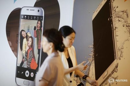 Women walk past an advertisement promoting a Samsung Electronics smartphone at its headquarters in Seoul