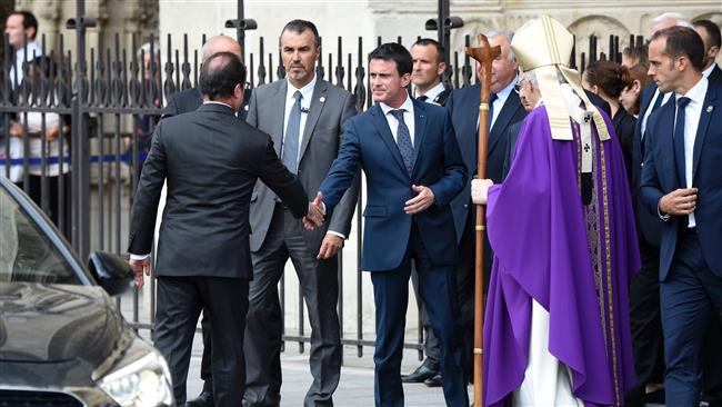 French President Francois Hollande shakes hands with French Prime Minister Manuel Valls next to French Cardinal Andre Vingt Trois after a Mass at the Notre Dame Cathedral to pay tribute to priest Jacques Hamel killed on July 26 in his church