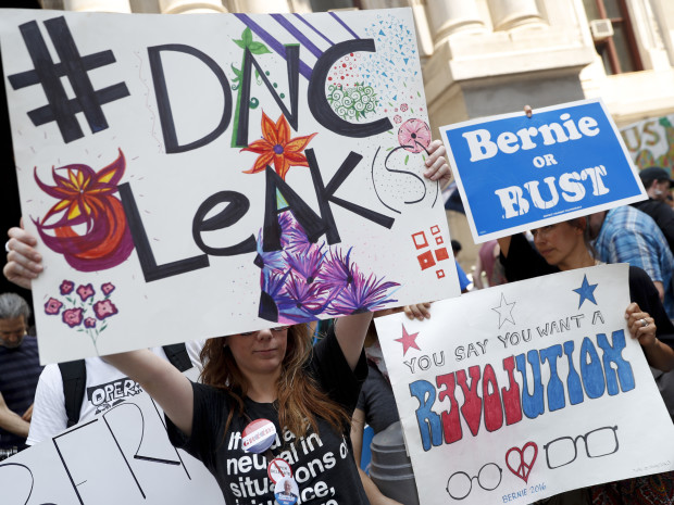 Demonstrators held signs outside the Democratic National Convention on Monday in Philadelphia. On Sunday Debbie Wasserman Schultz announced she would step down as DNC chairwoman at the end of the party's convention after thousands of internal DNC