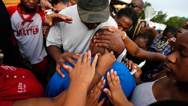 FILE- Cameron Sterling son of Alton Sterling is comforted by hands from the crowd at a vigil outside the Triple S convenience store in Baton Rouge La. Wednesday