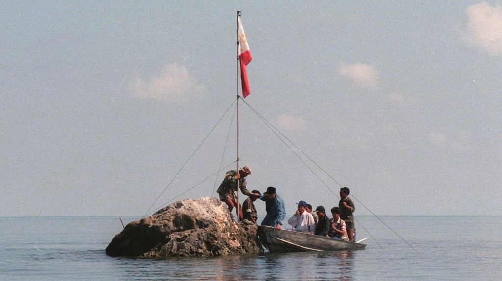 Philippine navy personnel and congressmen land at a rock that is part of Scarborough Shoal bearing the Philippine flag that was earlier planted by Filipino fishermen