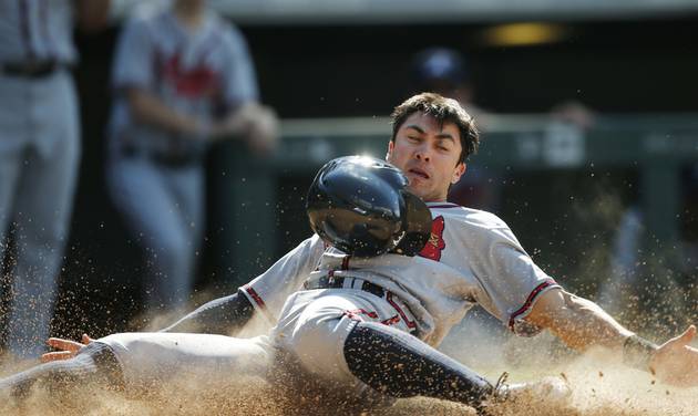 Atlanta Braves&#039 Chase d'Arnaud slides safely across home plate as he scores on a double hit by Freddie Freeman off Colorado Rockies relief pitcher Gonzalez Germen in the seventh inning of a baseball game Sunday