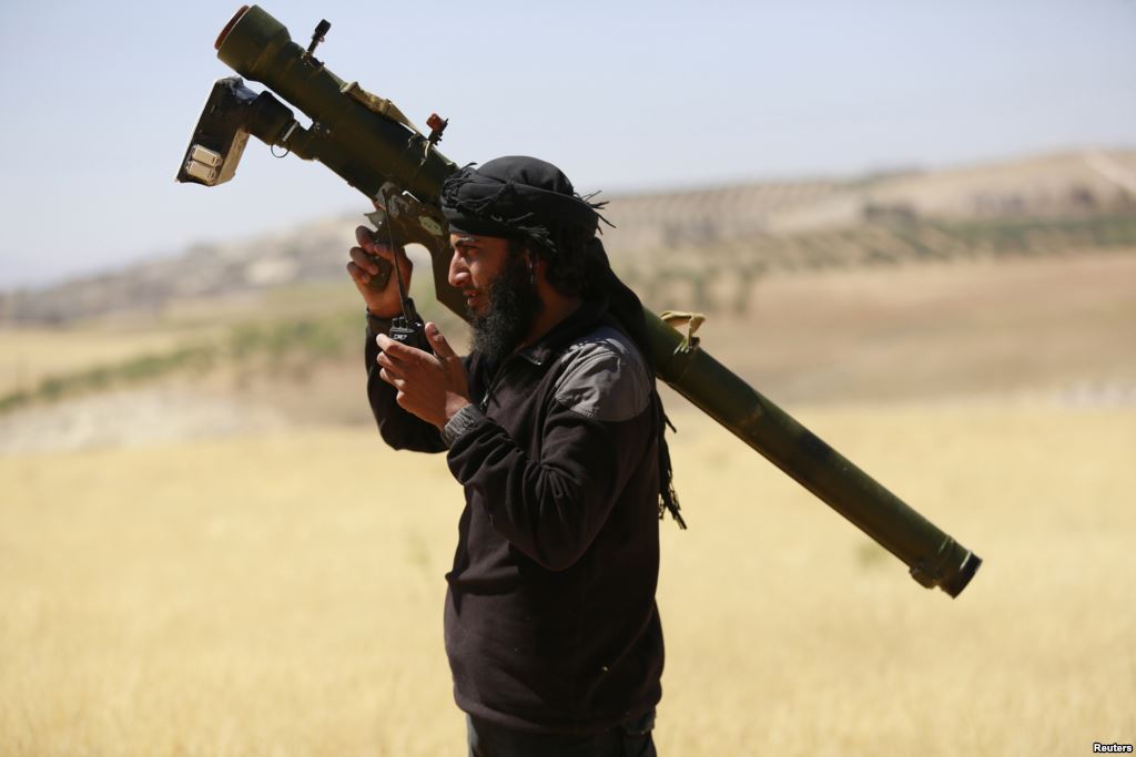 FILE- An Islamist Syrian rebel group Jabhat al Nusra fighter talks on a walkie-talkie while carrying his weapon in the northern Idlib province