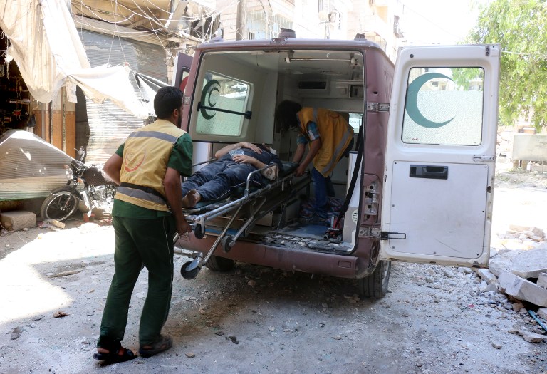 Emergency services evacuate a body after a barrel bomb struck just outside the Omar bin Abdaziz hospital in the Maadi district of the northern Syrian city of Aleppo following government air raids on rebel-held districts of the city