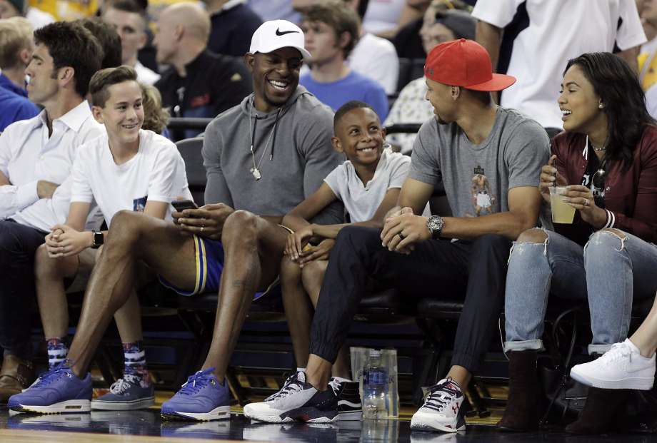 Andre Iguodala laughs with Stephen Curry as they watch the game with their families during the first half as the USA Mens National basketball team played the China Mens National team at Oracle Arena in an exhibition game in Oakland