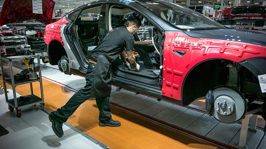 Workers assemble cars on the line at Tesla's factory in Fremont