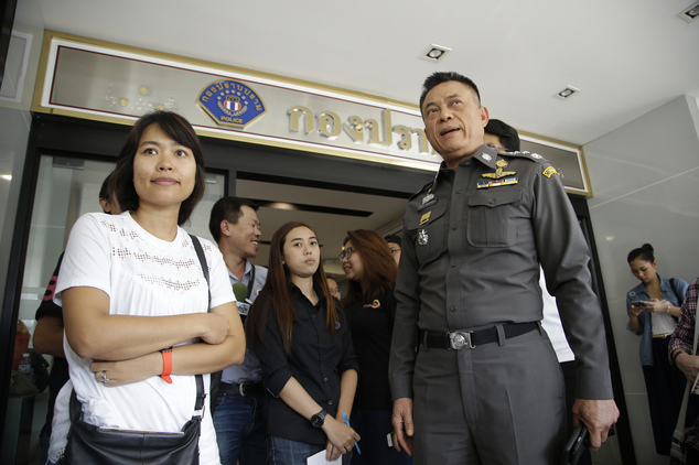 Police Lt. Gen. Thitiraj Nhongharnpitak stands with Noppawan'Ploy Bunluesilp wife of British journalist Andrew Mc Gregor Marshall as she prepares to leave