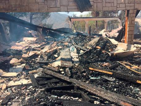 The remains of a burned home smoulder in Iron Canyon Road area near Santa Clarita California