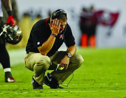 Then-Tampa Bay Buccaneers head coach Greg Schiano crouches on the field during a time out on Sept.15 2013 in Tampa Florida | Courtesy of TNS