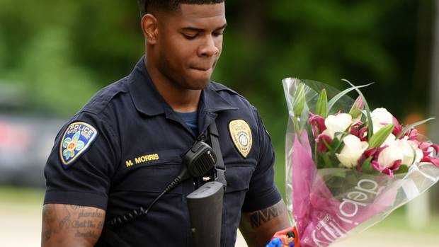 Baton Rouge officer Markell Morris holds a bouquet of flowers and a Superman action figure left at the Our Lady of the Lake Hospital where the police casualties were brought