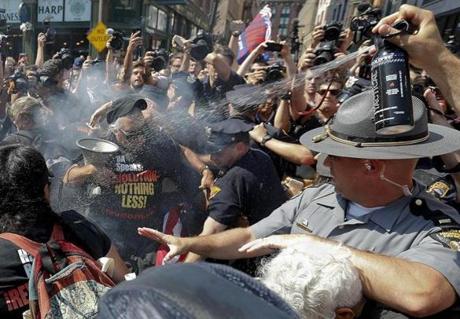 A police officer tries extinguish a burning American flag on Wednesday in Cleveland during the third day of the Republican convention