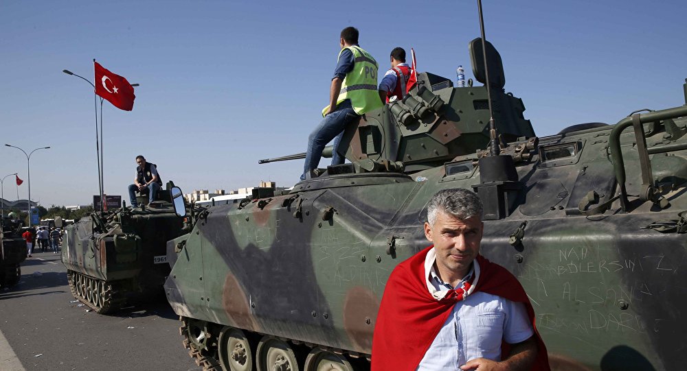 A man wrapped in a Turkish flag stands next to military vehicles in front of Sabiha Airport in Istanbul Turkey