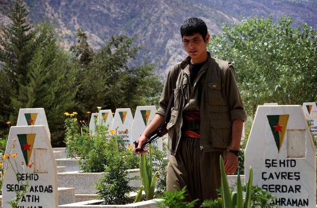 A member of the Kurdistan Workers Party walks past graves at a cemetary