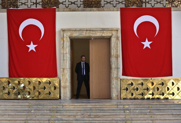 A Turkish parliament security man stands guard next to the broken yellow copper doors laid on the ground at the entrance of the assembly hall at the parliame