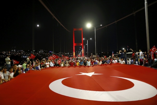 Pro-government demonstrators hold a giant Turkish flag during a march over the Bosphorus Bridge from the Asian to the European side of Istanbul Turkey